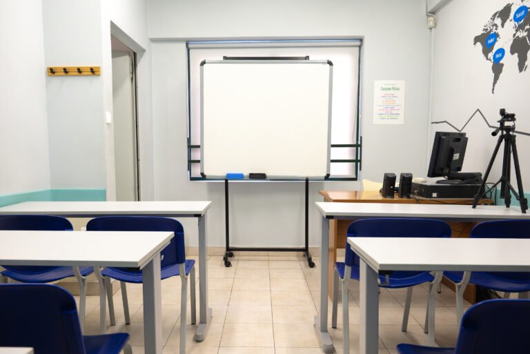 Modern classroom interior with student desks, blue chairs, and a whiteboard.